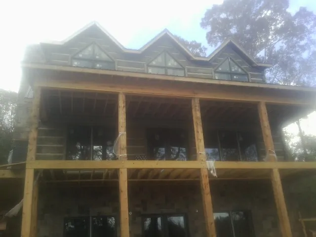Dormers and porch framing on a large log home under construction — Roof Coating work by our crew in Tecumseh