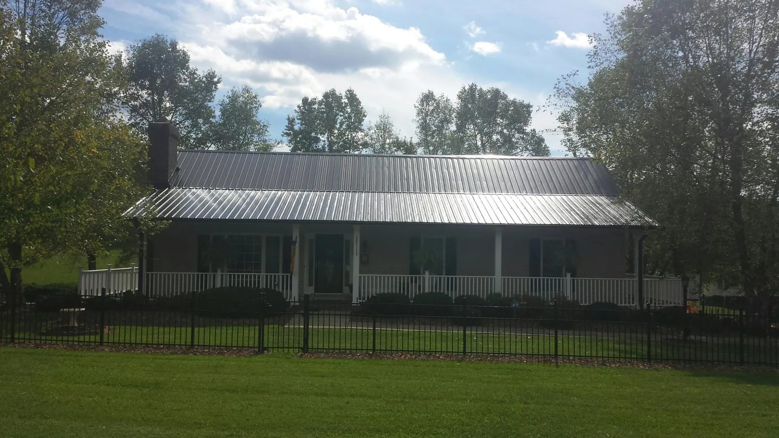 Gray metal roof on a brick ranch with a full width front porch — Gutter Guard Installation work by our crew in Tecumseh