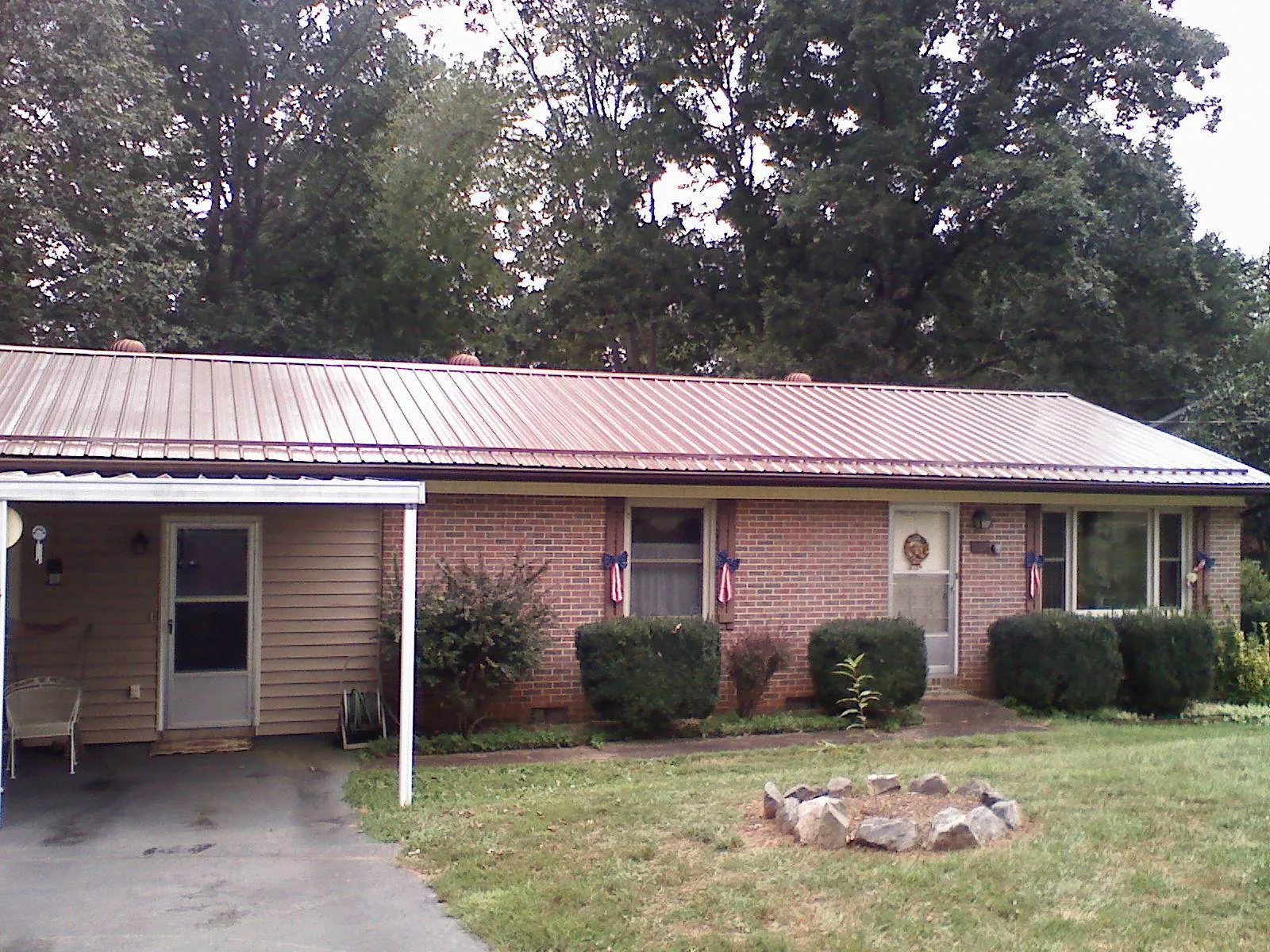 Bronze metal roof and carport on a brick ranch home — Roof Repair work by our crew in Tecumseh